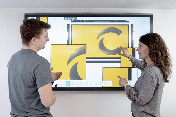 Two colleagues reviewing design drafts on an interactive display